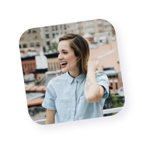 Portrait d’une jeune femme souriante, habillée en chemise claire, debout en extérieur urbain, incarnant la convivialité et la modernité des agents actifs de Naya.